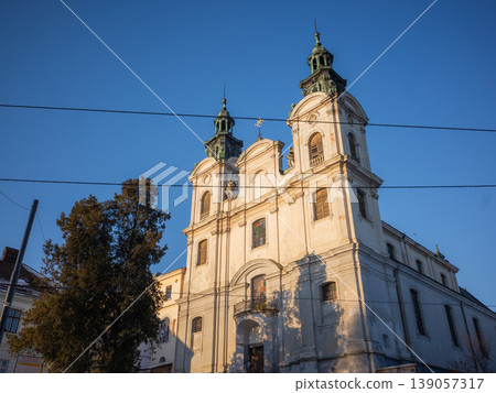 [Ukraine] Historic buildings in the old town of Lviv in western Ukraine, illuminated by the evening sunlight, against a clear blue sky. 139057317
