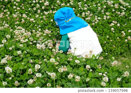一個孩子背對著鏡頭，坐在一片白三葉草花田中。 139057996