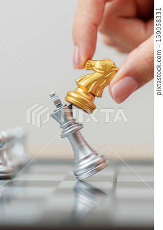 hand moving gold Chess knight figure and Checkmate opponent during chessboard competition. Strategy, Success, management, business planning, win, disruption, Trade war and leadership concept 139058331