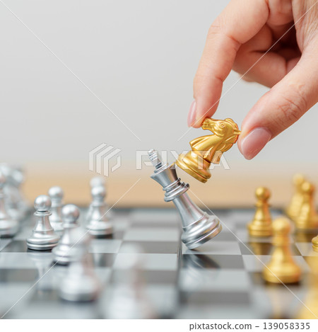 hand moving gold Chess knight figure and Checkmate opponent during chessboard competition. Strategy, Success, management, business planning, win, disruption, Trade war and leadership concept 139058335