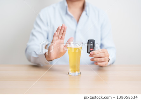 Responsible man reject a drink before driving for road safety, Man making stop hand gesture to refuse a glass of Beer and car remote. Avoid drink and drive, Drunk Driving Law concept 139058534