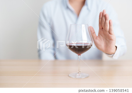 man making stop hand gesture to refuse a glass of Wine, Healthy man say no to alcohol drink, stop alcoholism and addiction concept. Responsible man reject a drink before driving and quit booze man making stop hand gesture to refuse a glass of Wine, Healthy man say no to alcohol drink, stop alcoholism and addiction concept. Responsible man reject a drink before driving and quit booze 139058541