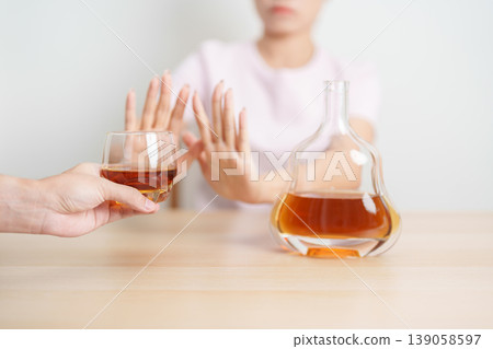 woman making stop hand gesture to refuse a glass of Cognac, Healthy man say no to alcohol drink, stop alcoholism and addiction concept. Responsible man reject a drink before driving and quit booze woman making stop hand gesture to refuse a glass of Cognac, Healthy man say no to alcohol drink, stop alcoholism and addiction concept. Responsible man reject a drink before driving and quit booze 139058597