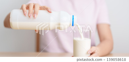 Healthy woman pouring fresh milk into glass at home, female drinking for calcium and strong bones, high protein, dairy product for healthy lifestyle, wellness and daily routine concept Healthy woman pouring fresh milk into glass at home, female drinking for calcium and strong bones, high protein, dairy product for healthy lifestyle, wellness and daily routine concept 139058618