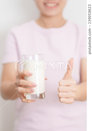 Healthy woman with glass of fresh milk and show thumbs up at home, female drinking for calcium and strong bones, high protein, dairy product for healthy lifestyle, wellness and daily routine concept Healthy woman with glass of fresh milk and show thumbs up at home, female drinking for calcium and strong bones, high protein, dairy product for healthy lifestyle, wellness and daily routine concept 139058623