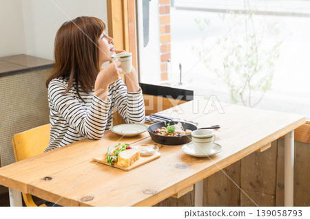 A young woman sipping coffee and gazing out the window. 139058793
