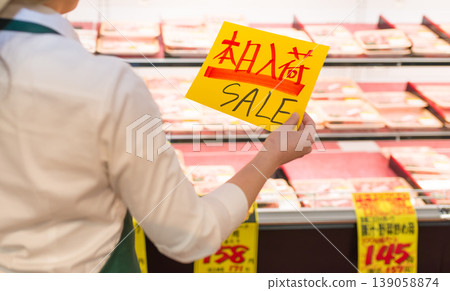 店員舉著一塊寫著「促銷」的黃色牌子。 店員舉著一塊寫著「促銷」的黃色牌子。 139058874