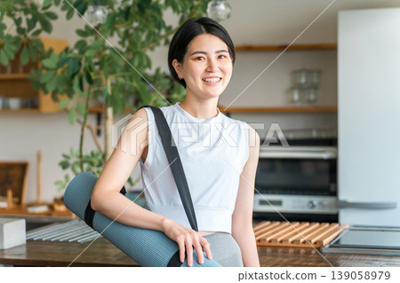 Woman holding yoga mat at home (workout, yoga, pilates) Woman holding yoga mat at home (workout, yoga, pilates) 139058979