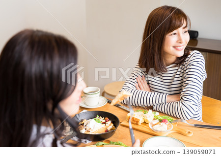 Two women enjoying lunch and conversation at a cafe; a relaxed moment on their day off. 139059071