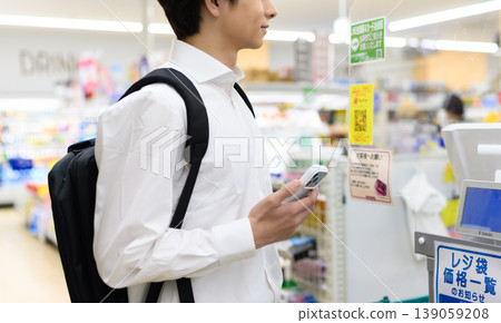 A man pays for his purchases at a supermarket using his smartphone. A man pays for his purchases at a supermarket using his smartphone. 139059208