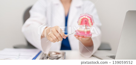 Dentist with tooth Anatomy model. Oral Teeth and disease, Scrape off tartar. March Oral health, Dentist Day, False Teeth. Toothache and Children Dental Health Month and Orthodontic Health Day Dentist with tooth Anatomy model. Oral Teeth and disease, Scrape off tartar. March Oral health, Dentist Day, False Teeth. Toothache and Children Dental Health Month and Orthodontic Health Day 139059552