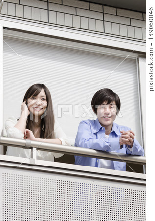 A young couple looking at us from their balcony A young couple looking at us from their balcony 139060046