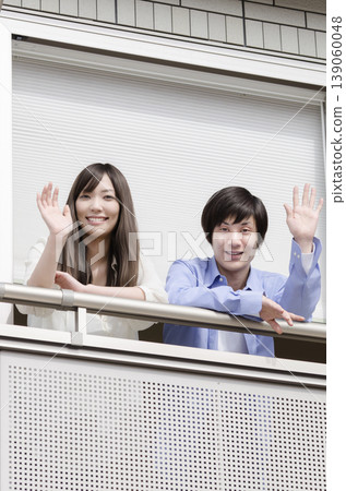 A young couple waving from their balcony A young couple waving from their balcony 139060048