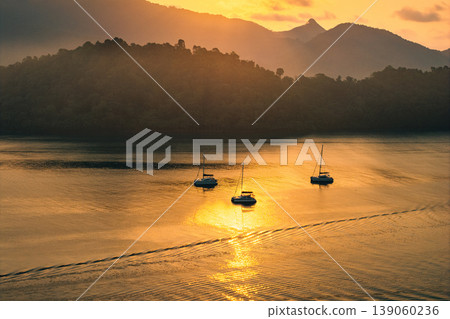 Aerial view of catamaran yachts anchored in a calm tropical bay during golden hour. Aerial view of catamaran yachts anchored in a calm tropical bay during golden hour. 139060236