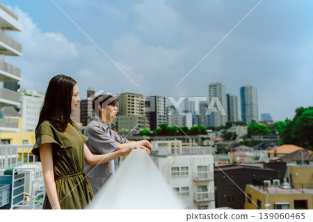 Two people gazing at the view from a rooftop in the city. Two people gazing at the view from a rooftop in the city. 139060465