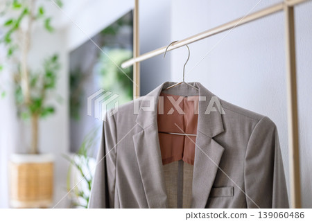 A gray jacket hanging on a clothes rack 139060486