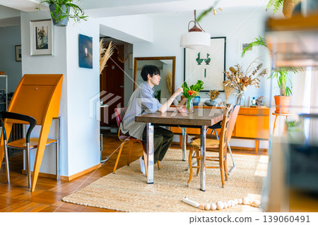 A young man looking at flowers in the dining room. 139060491