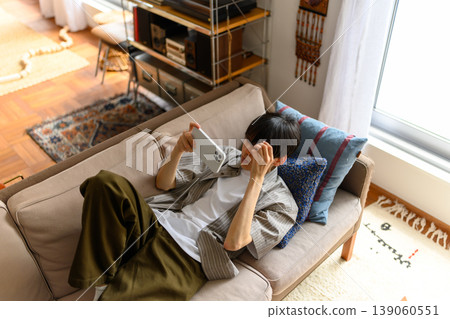 一名男子坐在沙發上,盯著他的智慧型手機。 一名男子坐在沙發上,盯著他的智慧型手機。 139060551
