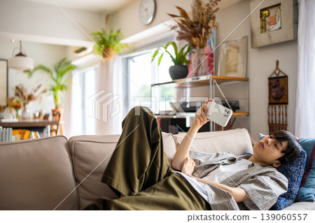 A young man is using his smartphone on a sofa. A young man is using his smartphone on a sofa. 139060557
