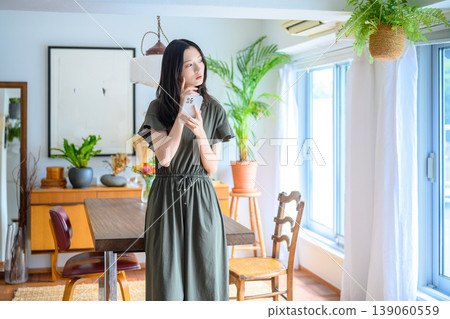 一位女士在房間裡拿著智慧型手機思考。 139060559