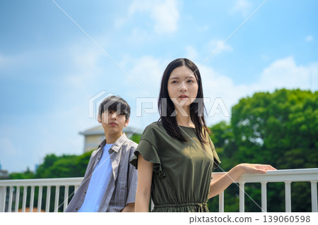 一位年輕女子和一位男子站在城市景觀背景下。 一位年輕女子和一位男子站在城市景觀背景下。 139060598