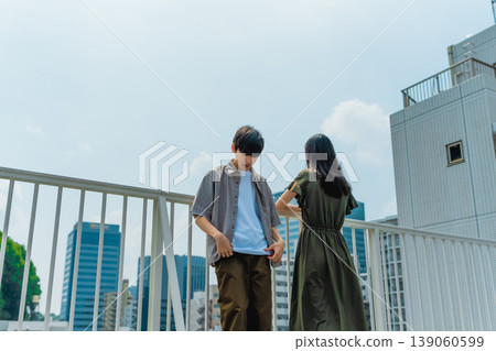 一對年輕男女站在屋頂上俯瞰城市。 139060599