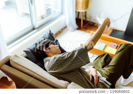 A man is lying on a sofa and using his smartphone. A man is lying on a sofa and using his smartphone. 139060602