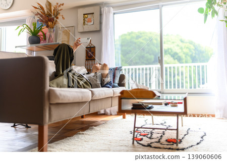 A person lying on a sofa, staring at their smartphone. 139060606
