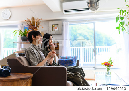 A man and a woman sitting side by side on a sofa A man and a woman sitting side by side on a sofa 139060610