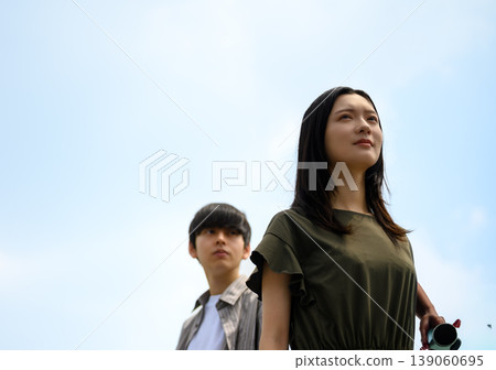 A woman with a camera and a man in the background. A woman with a camera and a man in the background. 139060695