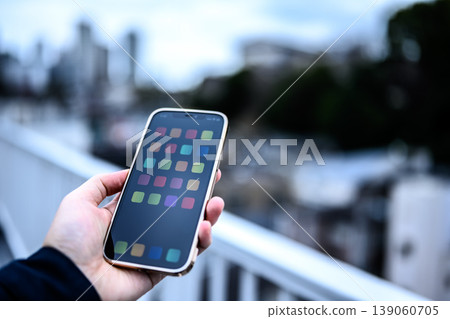 Hands holding a smartphone outdoors 139060705