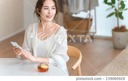 一位時尚女士在下午茶時間於客廳的餐桌旁放鬆休息。 一位時尚女士在下午茶時間於客廳的餐桌旁放鬆休息。 139060928