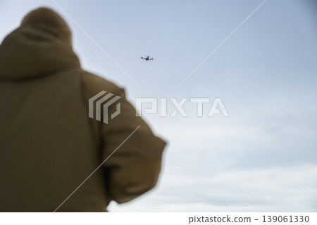 Soldier watching drone flying in cloudy sky Soldier watching drone flying in cloudy sky 139061330