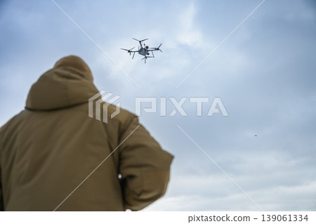 Rear view of soldier watching drone flying in cloudy sky Rear view of soldier watching drone flying in cloudy sky 139061334