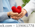 Doctor giving a red heart to senior patient in hospital. 139061778