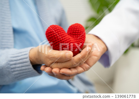 Doctor giving a red heart to senior patient in hospital. 139061778
