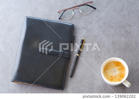 Image of a man working at his desk with a system organizer while drinking a cafe latte, a coffee with plenty of milk Image of a man working at his desk with a system organizer while drinking a cafe latte, a coffee with plenty of milk 139062202