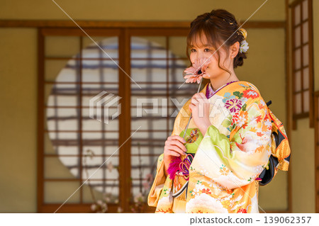 A young Japanese woman wearing a furisode kimono in a Japanese-style room (coming-of-age ceremony, graduation ceremony, wedding). A young Japanese woman wearing a furisode kimono in a Japanese-style room (coming-of-age ceremony, graduation ceremony, wedding). 139062357