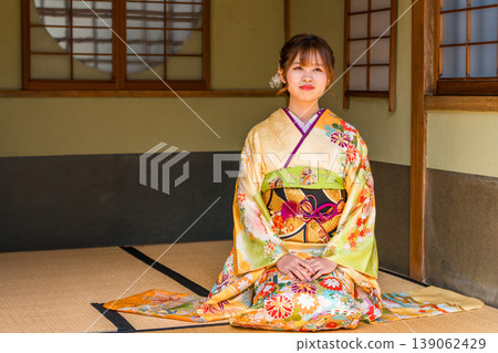 A young Japanese woman in a furisode kimono sits on the tatami mat in a Japanese-style room (coming-of-age ceremony, 20th birthday celebration). A young Japanese woman in a furisode kimono sits on the tatami mat in a Japanese-style room (coming-of-age ceremony, 20th birthday celebration). 139062429