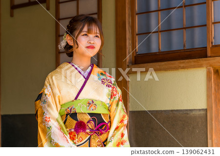 一位穿著振袖和服的日本年輕女子坐在日式房間的榻榻米上（成年禮，20歲生日慶祝活動）。 139062431