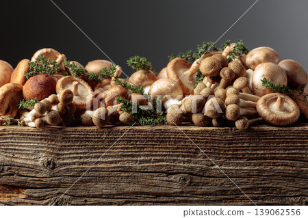 An assortment of mushrooms on a rustic wooden board with sprigs of thyme. 139062556