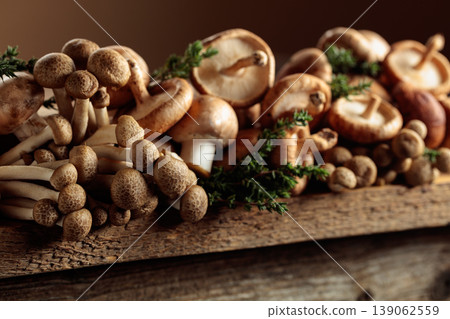 An assortment of mushrooms on a rustic wooden board with sprigs of thyme. 139062559