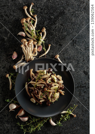 Fried shimeji mushrooms with thyme and garlic on a black plate. Fried shimeji mushrooms with thyme and garlic on a black plate. 139062564