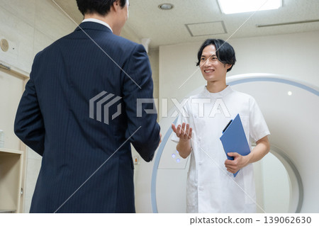 A businessman and a doctor maintaining a hospital's CT scanner. Filming assistance provided by: Denpa Gakuen Educational Foundation, Tokyo Electronics College. A businessman and a doctor maintaining a hospital's CT scanner. Filming assistance provided by: Denpa Gakuen Educational Foundation, Tokyo Electronics College. 139062630