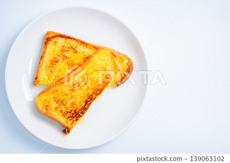 A close-up of honey-covered French toast, presented on a white plate, resembling a breakfast image. 139063102
