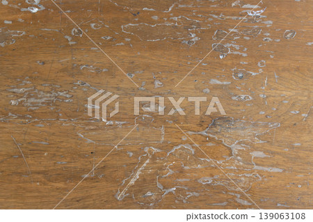 An old wooden board with the surface coating peeled off, revealing the wood grain irregularly. 139063108