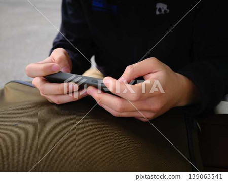 Hands of a man looking at a smartphone Hands of a man looking at a smartphone 139063541