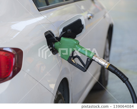 Gas pump nozzle in the fuel tank of a white car, refuel Gas pump nozzle in the fuel tank of a white car, refuel 139064084