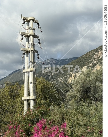 Utility pole and power lines in nature landscape with mountains and cloudy sky in the background 139064682