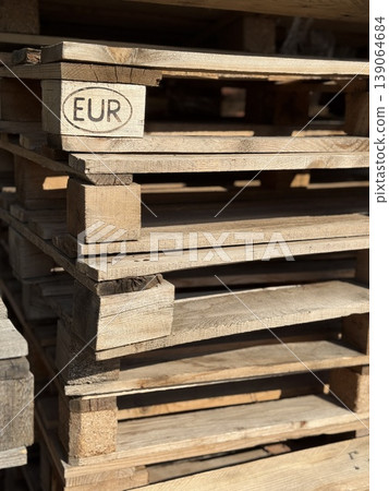 Wooden pallets stacked in a warehouse with natural light and texture, suitable for background 139064684